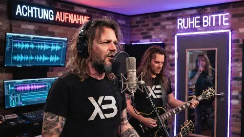 Premium Rock T-Shirt im Tonstudio - Sänger und Gitarrist in Studio vor Aufnahmeschirmen und Neon-Schriftzügen mit XB-Premium Rock T-Shirt.