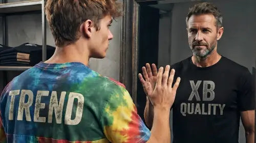 Junger Mann mit einfachem Trend-T-Shirt sieht sein älteres ich im Spiegel, dass ein Premium Rock T-Shirt von XB trägt.