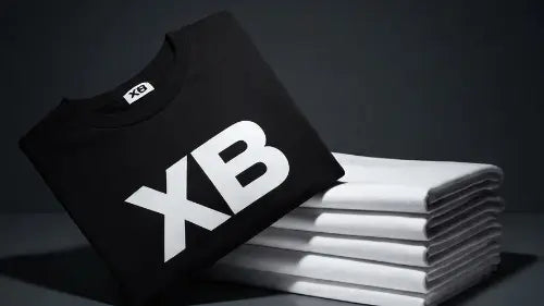 Ein hochwertiges Premium Rock T-Shirt aus 100% gekämmter Baumwolle mit dem Aufdruck XB neben einem Stapel gekämmter Baumwolle.