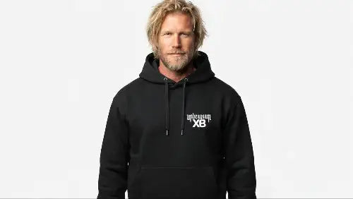 Blonder Mann mit Bart trägt schwarzen Premium Heavyweight Rock Hoodie mit   unbeugsam XB Print.