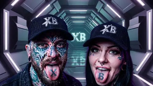 Paar im Tunnel streckt die Zunge raus: Beide tragen ein schwarzes Premium Rock Cap aus 100% Bio-Baumwolle mit hochwertigem XB-Premium Stick-Design.