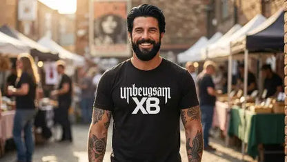  Dunkelhaariger Mann mit Bart trägt hochwertiges schwarzes Premium Rock T-Shirt aus 100 % gekämmter Baumwolle und einer Grammatur von 185g/m² sowie XB Unbeugsam Design aus Öko-Tex zertifizierten Farben.