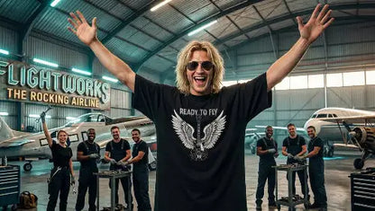 Rockiger Mann im Flugzeug-Hangar trägt hochwertiges schwarzes Premium Rock T-Shirt aus 100 % Bio-Baumwolle mit einer Grammatur von 240g/m² sowie komplexem Flügel Design aus Öko-Tex zertifizierten Farben.