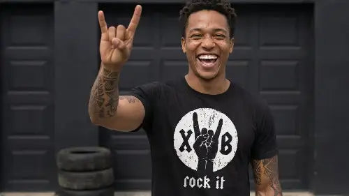 Junger schwarzer Mann trägt hochwertiges schwarzes Premium Rock T-Shirt aus 100 % gekämmter Baumwolle mit einer Grammatur von 185g/m¹ sowie komplexem XB-Hand Design aus Öko-Tex zertifizierten Farben.