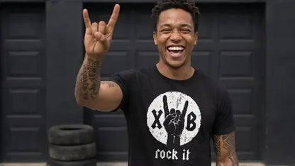 Junger schwarzer Mann trägt hochwertiges schwarzes Premium Rock T-Shirt aus 100 % gekämmter Baumwolle mit einer Grammatur von 185g/m¹ sowie komplexem XB-Hand Design aus Öko-Tex zertifizierten Farben.
