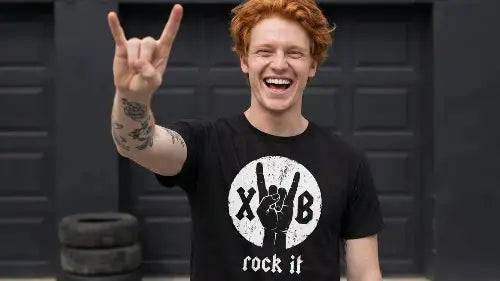 Rothaariger Mann trägt hochwertiges schwarzes Premium Rock T-Shirt aus 100 % gekämmter Baumwolle und einer Grammatur von 185g/m² sowie komplexem XB rock it-Hand Design aus Öko-Tex zertifizierten Farben.