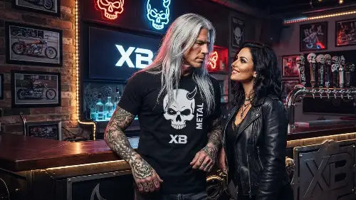 Rocker mit hochwertigem Premium Rock T-Shirt aus 100% gekämmter Baumwolle &  Öko-Tex  zertifizierten Farben im Skull-Stil-Design an der Bar schaut Frau tief in die Augen.