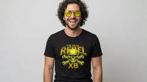 Lachender Mann mit schwarzem Premium Rock T-Shirt mit gelbem Totenkopf-Print und THE REAL REBEL XB Schriftzug.