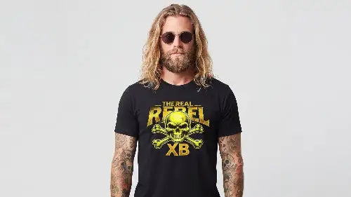 Blonder Mann mit Sonnenbrille und langem Haar trägt schwarzes Premium Rock T-Shirt mit komplexem Skull-Design THE REAL REBEL.