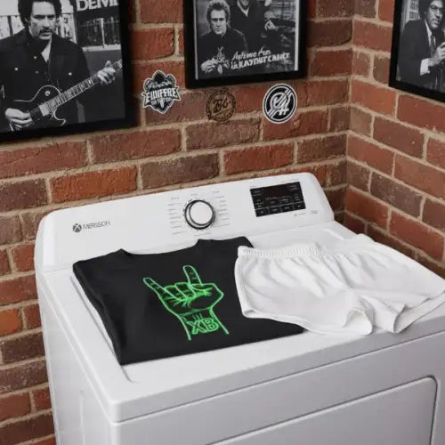 Auf eine Waschmaschine liegt ein Premium Rock T-Shirt für Männer mit XB-Rock-Hand-Design.