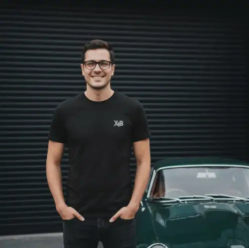 Mann steht stolz vor seiner Garage und trägt ein diskretes Premium Rock T-Shirt für Männer.