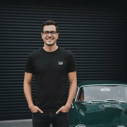 Mann steht stolz vor seiner Garage und trägt ein diskretes Premium Rock T-Shirt für Männer.