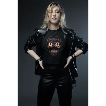 Eine junge Dame trägt ein Rock T-Shirt für Frauen.Das schwarze Damen Premium T-Shirt hat den Aufdruck eines Totenkopfes in dessen leuchtenden Augen Frauen tanzen sowie die Aufschrift Rockstar.