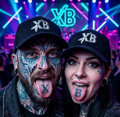Rockiges Paar streckt Zunge raus und trägt dabei jeweils ein Premium Rock Cap in schwarz aus 100% Bio Baumwolle von XB mit komplexem Gitarre-XB-Design.